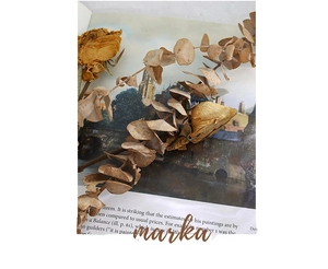 Detail of twisted tube necklace with dried eucalyptus and vintage roses on an art book