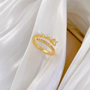 Detail of gold-plated ring with pearls and zircon set on white satin fabric