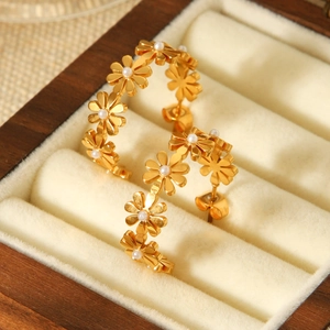 Close-up of 18K gold stainless steel flower earrings with pearls in a wooden jewelry box