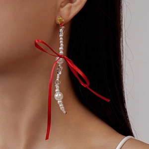 Détail de boucles d'oreilles à nœud rouge avec perles en cascade sur mannequin