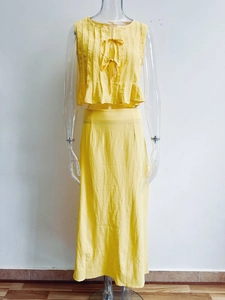 Detail of yellow cotton linen set featuring pleated sleeveless top with bow tie accents