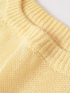 Vue détaillée de la texture maille fine et du bord côtelé du pull jaune