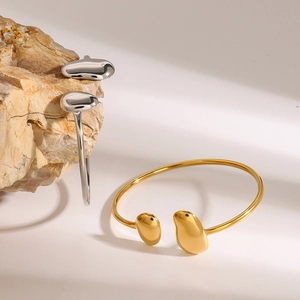 Bracelets ouverts en forme de goutte d'or et d'argent sur un fond de pierre naturelle