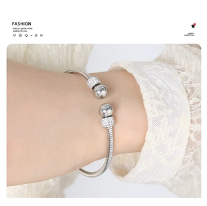 Detail view of silver snake chain bangle with polished beads and rhinestone ring detail