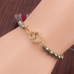 Detail of bohemian woven heart bracelet with gold accents on wrist