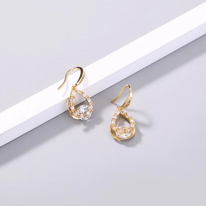 Detail of golden teardrop earrings with sparkling zircon inlay and elegant drop design