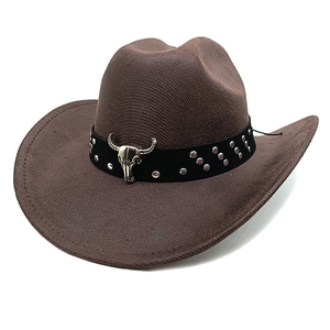 Detail of a brown cowboy hat featuring silver bull skull ornament and metallic studs