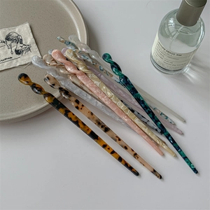 Épingles à cheveux spirales en acétate aux motifs marbrés sur un fond minimaliste chic