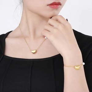 Ensemble collier et bracelet dorés élégants avec pendentifs haricot et perle sur mannequin
