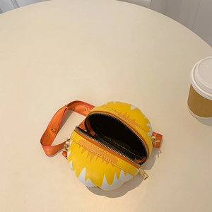 Detailed top view of a yellow cartoon dinosaur crossbody bag with orange strap on a beige table