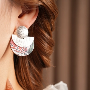 Close-up of geometric wood earrings with silver brushed metal and abstract pattern
