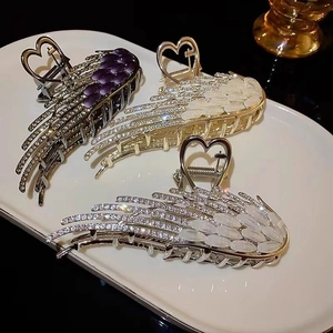 Exquisite angel wing hair claws with opal rhinestones on elegant ceramic display tray