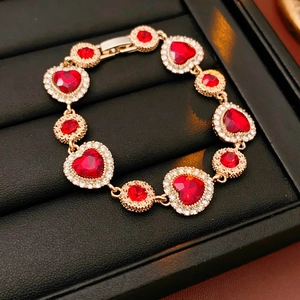Dettaglio di bracciale vintage dorato con gemme rosse e cristalli scintillanti