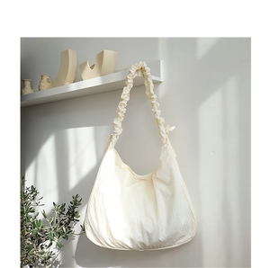 Detail of a beige oversized nylon shoulder bag with stylish ruched pleat strap design