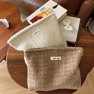 Close-up of thick textured beige and brown woven cosmetic bags on a wooden table