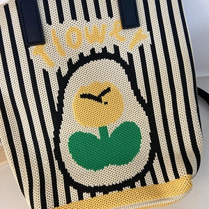 Close-up of knit tote bag featuring striped pattern and yellow flower embroidery