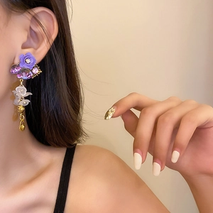 Detailed view of floral crystal earrings featuring purple stones and golden pendants
