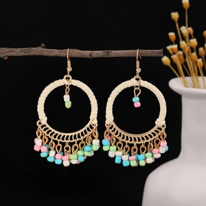 Detailed shot of bohemian round earrings with pastel seed bead tassels on a branch