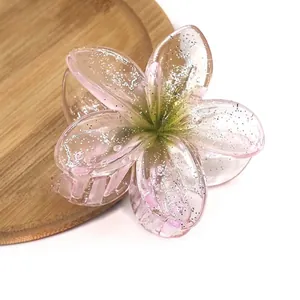 Detailed view of plumeria hair claw clip with pink gradient finish and silver glitter
