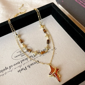 Close-up of double-layered gold star necklace with amber resin pendant on jewelry tray