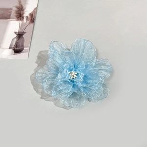 Détail de fleur en organza bleu clair avec perles centrales sur surface grise