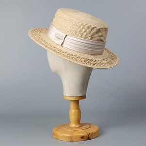 Close-up of beige boater hat with champagne satin ribbon and hollow weave brim detail