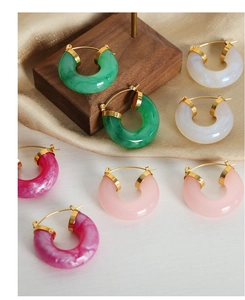 Detail view of colorful resin U-shaped earrings on elegant silk and wood background