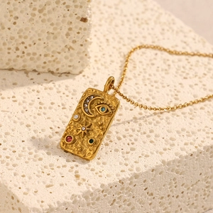 Macro view of 18K gold plated rectangular pendant with celestial moon and star embossing