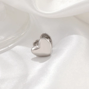 Elegant minimalist silver heart ear cuff on premium white silk background fabric