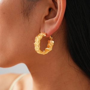 Detail of 24k gold-plated round hoop earrings with unique geometric woven texture on model
