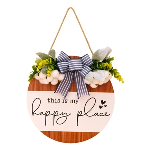 Detailed close-up of a rustic wood welcome sign with white cotton and greenery decoration