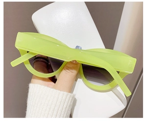 Detail of bright green cat eye sunglasses with dark UV protection lenses and glossy finish