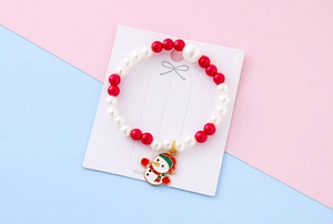 Detail of beaded Christmas bracelet featuring red white pearls and a cute snowman charm