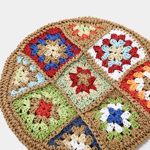 Close-up of handmade crochet flower pattern on a raffia straw beret with vibrant colors