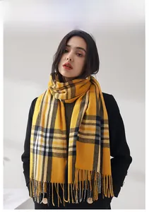 Detail of warm yellow and black plaid scarf featuring soft cashmere-like texture and tassels
