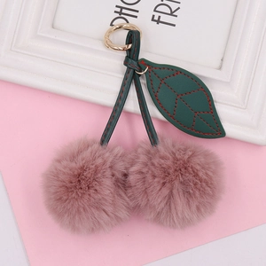 Detail of pink plush cherry keychain with green faux leather leaves and golden clasp
