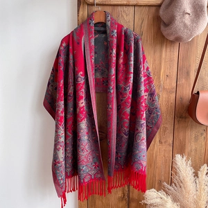 Close-up of red ethnic paisley shawl with fringe hanging next to retro fashion accessories