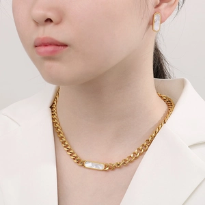 Close-up of 18K gold plated Cuban chain necklace and shell earrings on a model