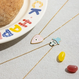 Detailed macro view of 18K gold stainless steel heart and Hamsa evil eye enamel pendants