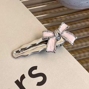 Detail shot of the pink enamel bow hair clip with silver metal base and rhinestones