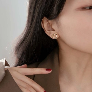 Close-up of golden crossover heart-shaped earrings on model for a stylish look