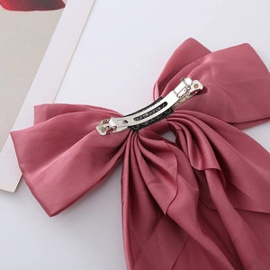 Detail of dusty pink satin bow hair clip featuring a secure silver metal spring clasp