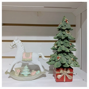 Close-up of resin rocking horse and Christmas tree figurine ornaments on a shelf