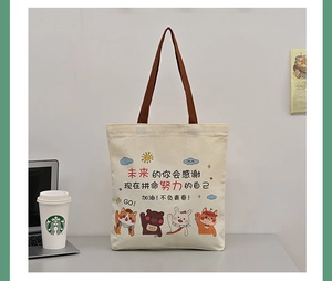 Canvas tote bag in study setting with laptop and inspirational cartoon character prints