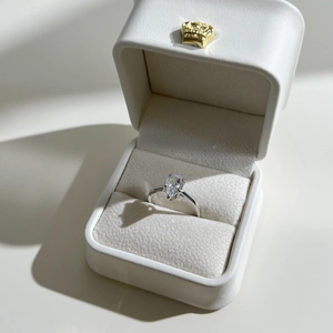 Anello con zirconia taglio a pera su scatola in pelle bianca con logo a corona d'oro