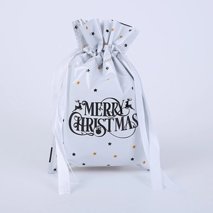 Close-up of white Merry Christmas drawstring gift bag with gold stars and reindeer