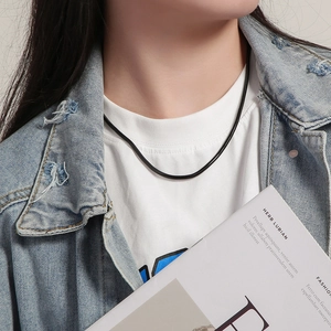 Detail shot of a minimalist matte black snake chain necklace on a model