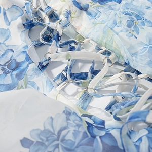 Détail d'une robe fleurie bleue avec anneau métallique argenté et liens croisés