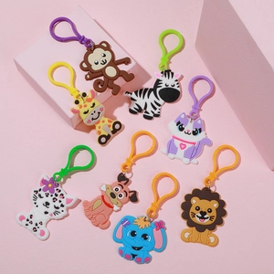 Detail of 8 cartoon animal PVC keychains including lion and zebra on pink props