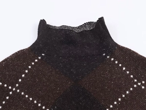 Detail of high collar knit sweater featuring brown and black argyle pattern and white stitching